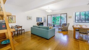 Un salon spacieux comprenant un canapé, un plancher en bois, une table à manger avec des chaises et un escalier.