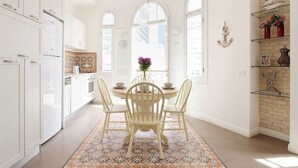 Een moderne keuken met witte kasten, een ronde eettafel met stoelen en een vloerkleed met een patroon.