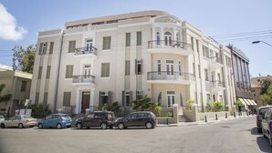 Een hotel met meerdere verdiepingen, balkons, geparkeerde auto's en een heldere lucht.