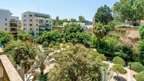 Zona residencial com edifícios modernos, vegetação exuberante e um jardim bem cuidado.