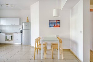 Una cocina moderna con armarios blancos, una mesa de comedor de vidrio y sillas de madera.