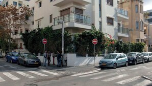A multi-story residential building with balconies, a pedestrian crossing, and parked cars. - Cute Shenkin area 1BR By Holiday-rentals SAFE ROOM ({{addressCityy}})