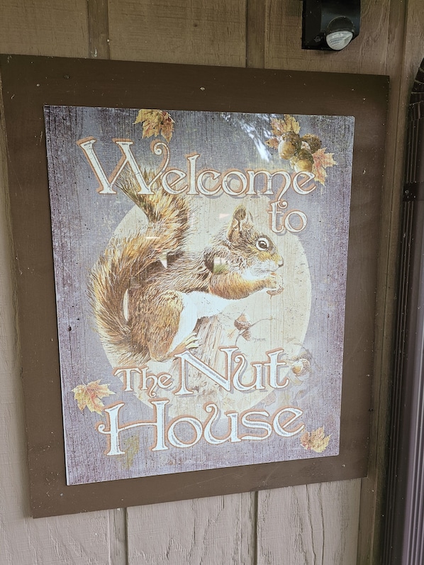 A framed welcome sign with a squirrel and the text "Welcome to the Nut House."