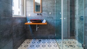 Ein modernes Badezimmer mit einem großen Spiegel, einem Aufsatzwaschbecken und einer Duschkabine.