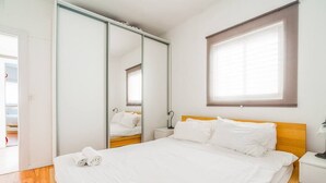 Ein Hotelzimmer mit einem Bett, einem Nachttisch, einem Spiegel und einem Fenster.
