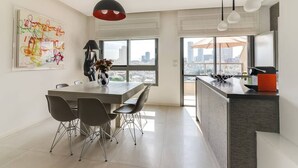 A modern kitchen with a dining area, large windows, and a city view. - Wonderfull duplex 3BR Hakovshim SAFE ROOM ({{addressCityy}})
