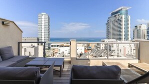 A rooftop terrace with outdoor seating, a view of the city skyline, and a clear sky. - Wonderfull duplex 3BR Hakovshim SAFE ROOM ({{addressCityy}})