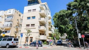 Ein mehrstöckiges Gebäude mit moderner Architektur, mit Balkonen und einer Mischung aus Wohn- und Geschäftsflächen.