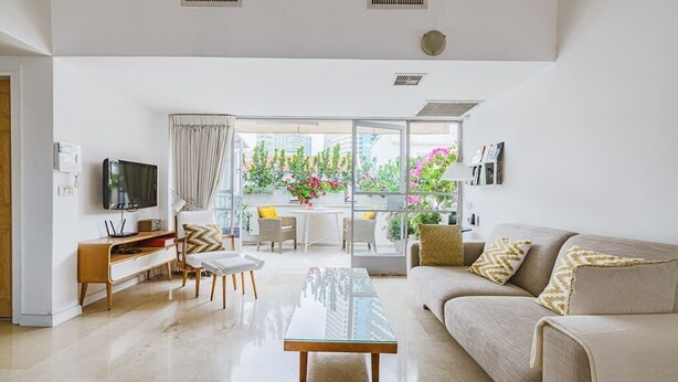 A modern living room with a sofa, coffee table, TV, and a dining area with chairs and a table.