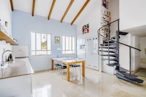 Una cocina moderna con comedor, una escalera y vistas al exterior.