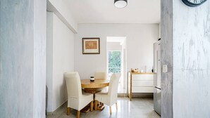 Une cuisine moderne avec un coin repas, comprenant une table et des chaises en bois, un réfrigérateur et une fenêtre donnant sur un paysage verdoyant.