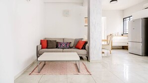 Un salon moderne comprenant un canapé, une table basse et un coin cuisine avec un réfrigérateur.