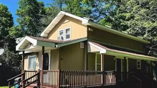 Ein eingeschossiges Haus mit Veranda, einer kleinen Terrasse und einer Treppe zum Eingang.