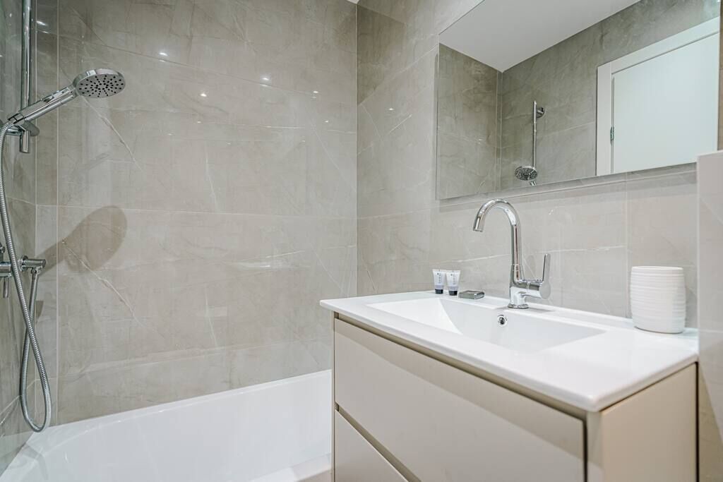 A modern bathroom with a bathtub, a shower, a sink, and a mirror.