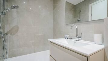 A modern bathroom with a bathtub, a shower, a sink, and a mirror.