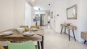 Un comedor moderno con una mesa de madera, sillas verdes y una cocina al fondo.