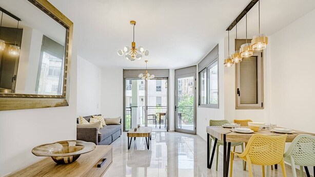 Una sala de estar moderna con un sofá, una mesa de centro y un comedor con sillas y una mesa.