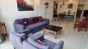 A modern living room with a grey sofa set, a wooden coffee table, and a dining area with a table and chairs. - Spacious 2BR  Ha-Medina Square SAFE ROOM (Tel Aviv-Yafo)