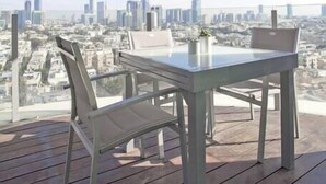 Un balcon avec une table et des chaises, donnant sur un panorama urbain.