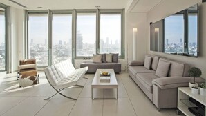 Un salon moderne avec de grandes fenêtres, un canapé blanc, un fauteuil blanc et une table basse.