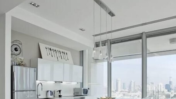 Une cuisine moderne dotée d’un grand îlot central, de tabourets de bar et offrant une vue sur la ville grâce à de grandes fenêtres.
