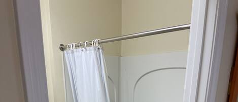 Una ducha a pie con puerta de vidrio, una bañera blanca y un tocador de madera.