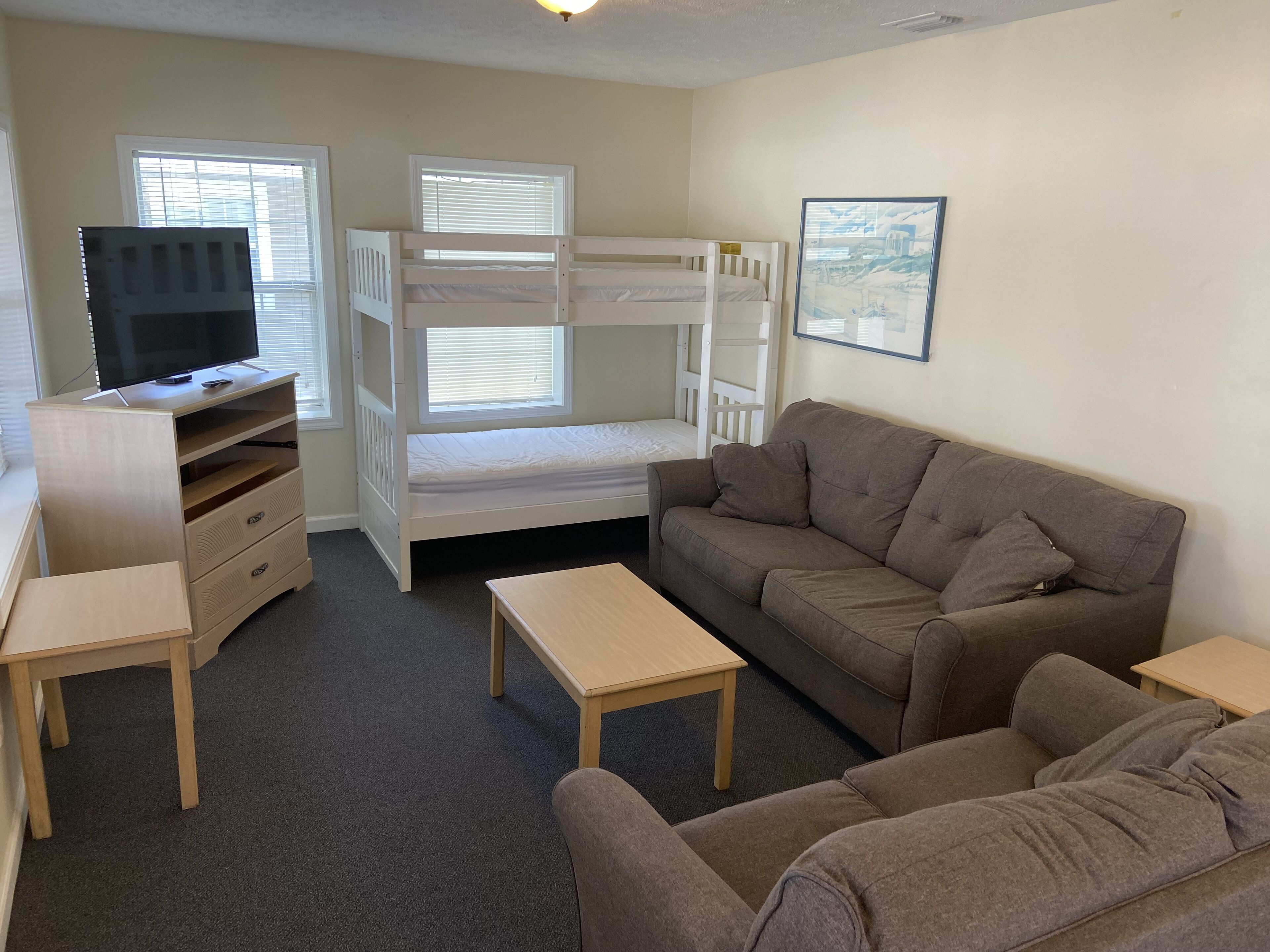 Une chambre avec des lits superposés, un canapé, une télévision et un bureau.