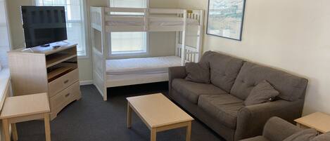 Une chambre avec des lits superposés, un canapé, une télévision et un bureau.