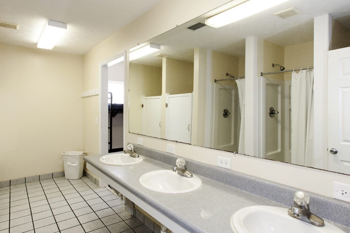 Un baño limpio y bien iluminado con dos lavamanos, un espejo grande y una zona de ducha.