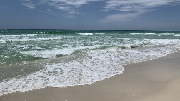 Een strand met golven en een heldere lucht.