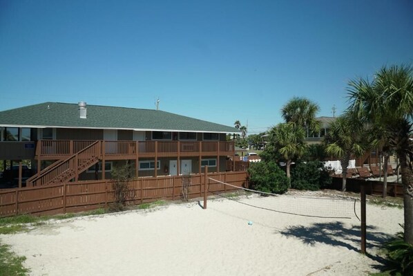 A beachfront hotel with a two-story structure, a balcony, and a sandy beach area. - Cottages Christian Retreat (Panama City Beach)