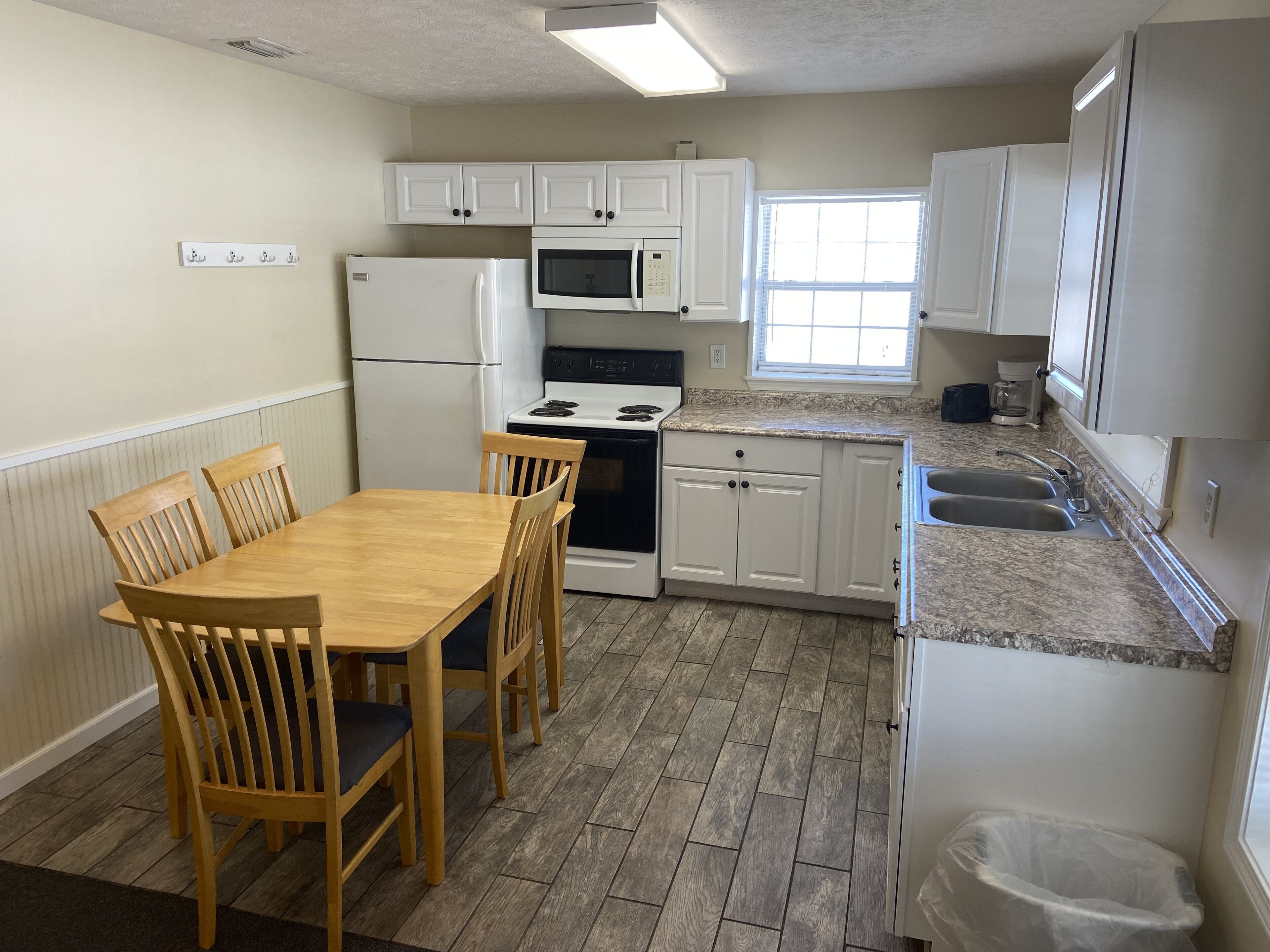 Una cocina con armarios blancos, una mesa de comedor de madera y sillas.