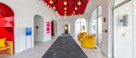 Een hotelhal met een centrale gang, zithoeken en een modern plafondontwerp.