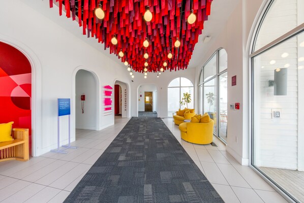 A hotel lobby with a central corridor, seating areas, and a modern ceiling design.