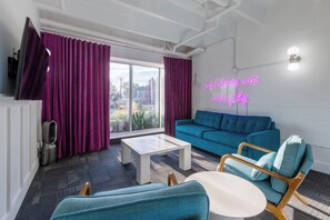 A modern living room with a blue sofa, a white coffee table, and a neon sign.