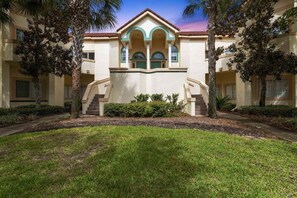 A hotel with a central courtyard, palm trees, and a symmetrical facade with arched windows.