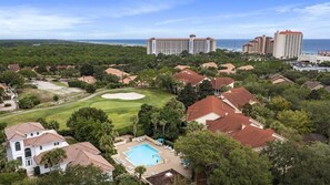 Un resort con piscina, campo da golf e hotel affacciati sulla spiaggia.