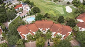 A residential area with a large house featuring a swimming pool, surrounded by lush greenery and a golf course.