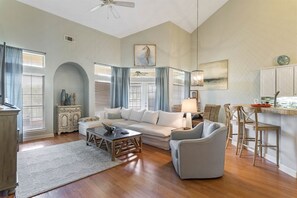 A spacious living room with a sofa, armchairs, a coffee table, and a dining area with bar stools.
