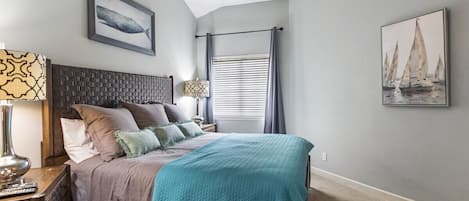 Un dormitorio con cama, mesita de noche, lámpara, ventana con cortinas y decoración en la pared.