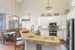 A modern kitchen with white cabinets, stainless steel appliances, and a central island with a built-in sink.