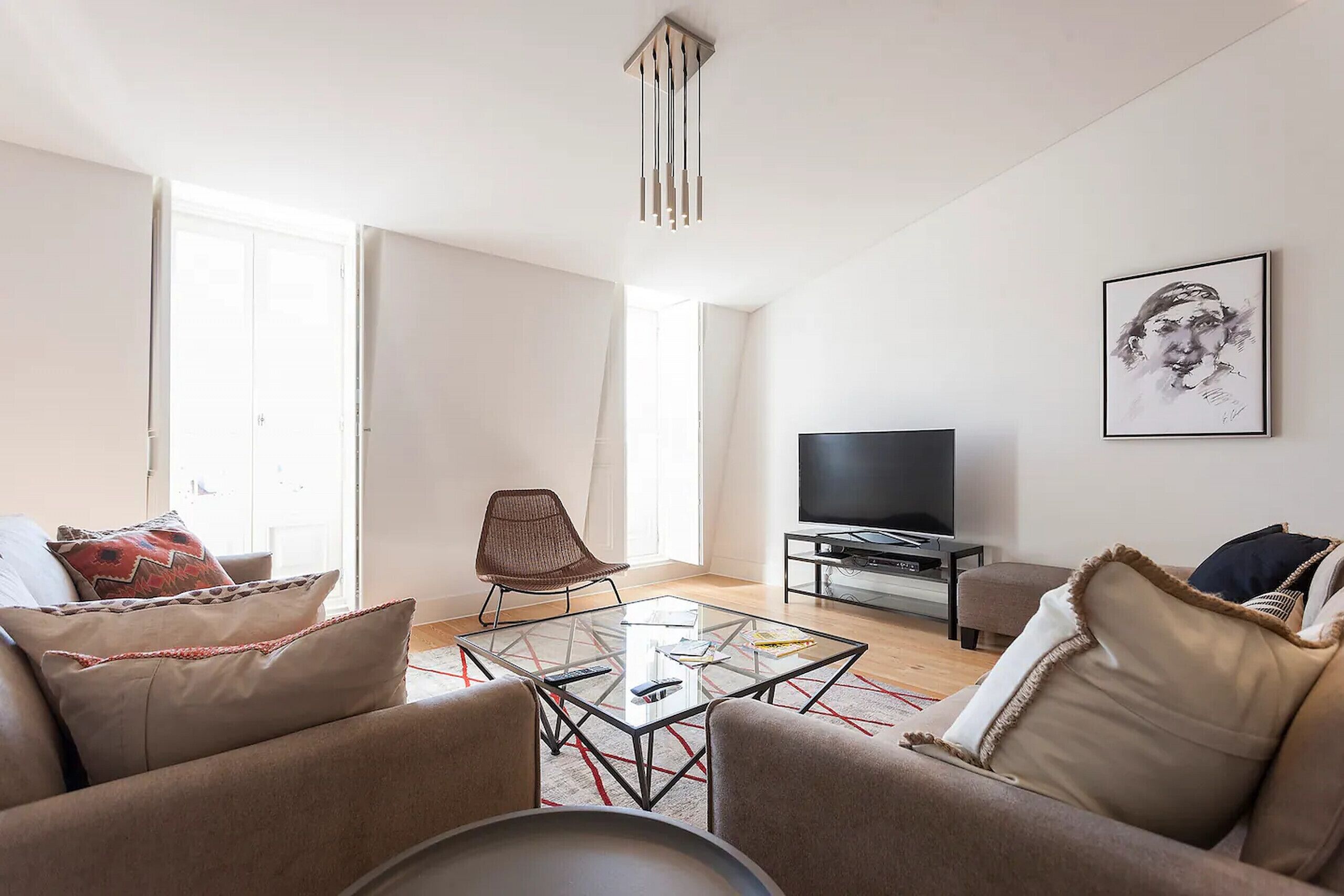 A modern living room with a glass coffee table, leather sofas, a TV, and a large window.