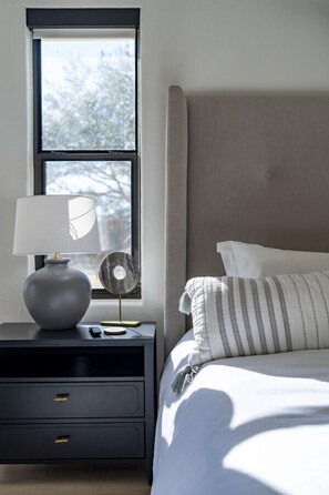 A bedroom with a bed, a nightstand with a lamp, and a window. - Luxury Ranch Retreat Pool, Sleeps 18 (Dripping Springs)