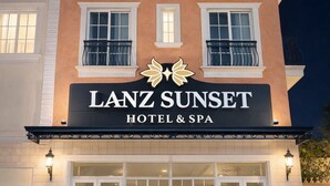 Ein mehrstöckiges Hotel mit Balkonen und großen Fenstern, mit dem Namen "LANZ SUNSET HOTEL & SPA".