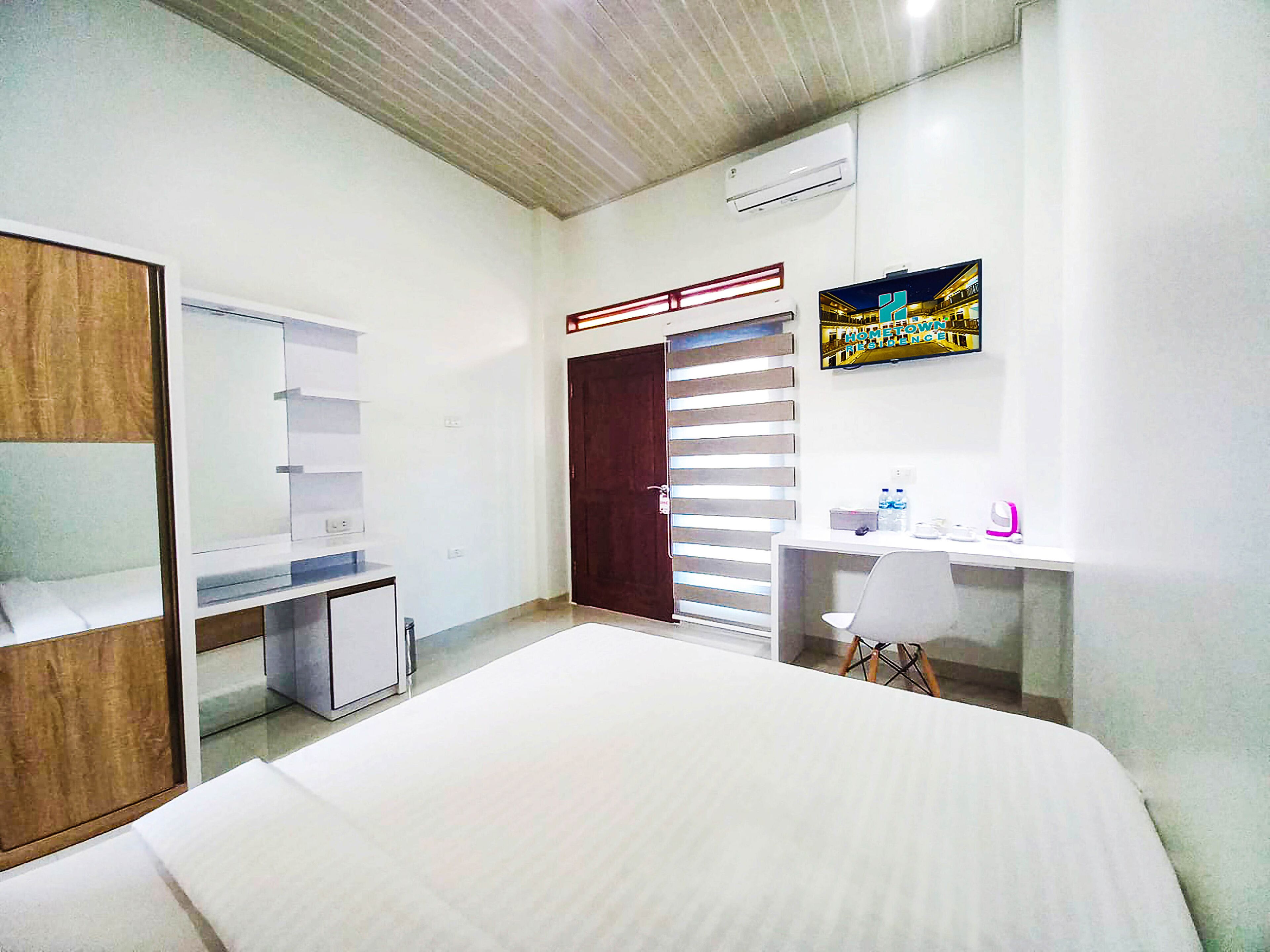 Un dormitorio con cama, escritorio, silla, armario y puerta con persianas.