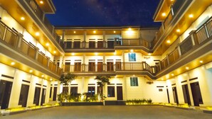 Un hotel de varios pisos con un patio central, balcones y vista al cielo nocturno.