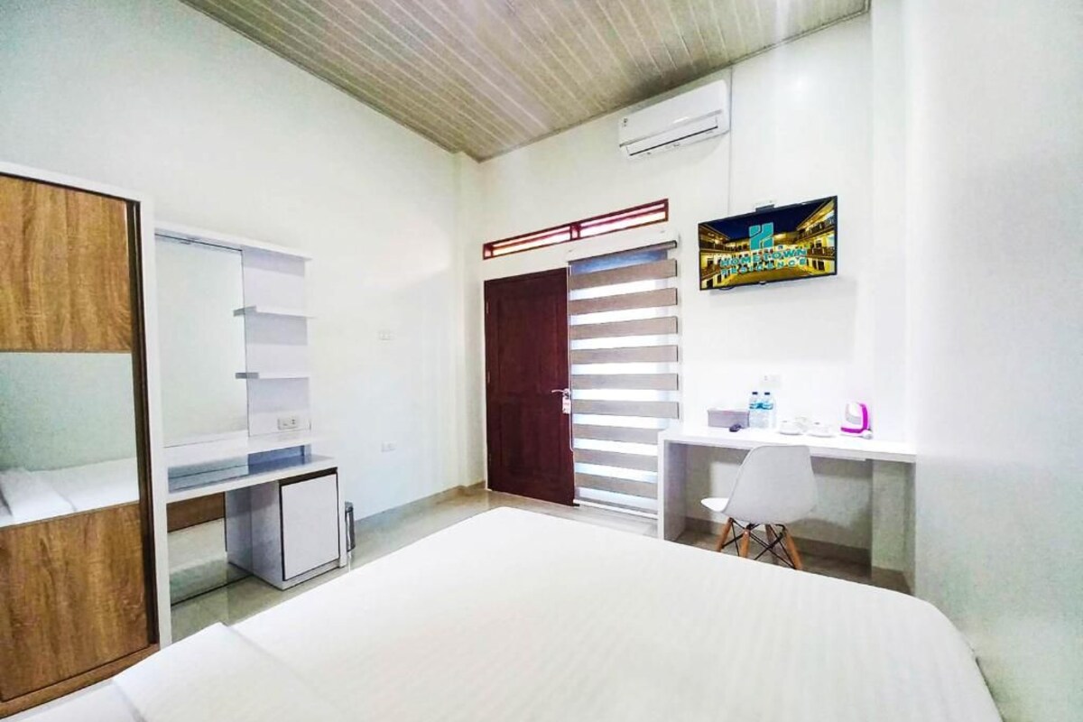 A bedroom with a bed, a wardrobe, a desk, and a chair.