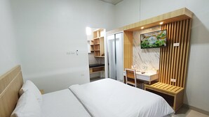 Una habitación de hotel moderna con una cama, un escritorio y un televisor montado en la pared.