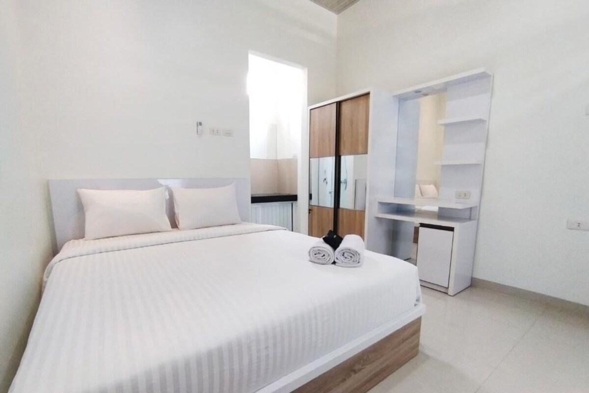 A modern bedroom with a large bed, a wardrobe, and a desk.