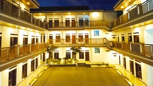 Un hotel de varios pisos con un patio central, balcones en cada planta y vista al cielo nocturno.